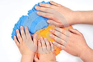 The hands of the mother and the child lie on the bright kinetic sand