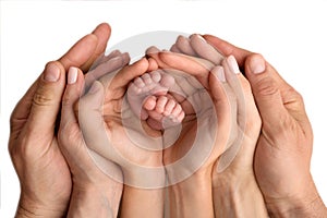 The hands of the mother, father and older child hold the feet of the newborn. Cute family portrait with baby.