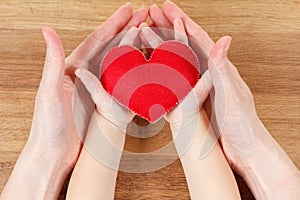 Hands of mother and son holding heart symbol