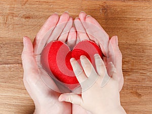 Hands of mother and son holding heart symbol