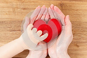 Hands of mother and son holding heart symbol