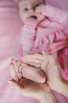 Hands of mother tenderly holding a tiny baby's legs.