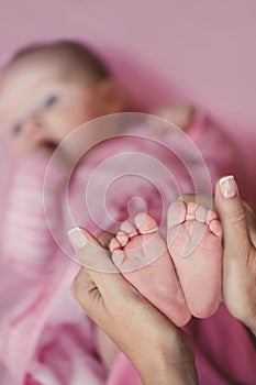 Hands of mother tenderly holding a tiny baby's legs.