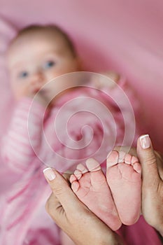 Hands of mother tenderly holding a tiny baby's legs.