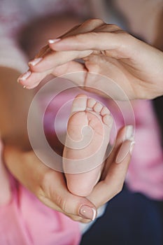 Hands of mother tenderly holding a tiny baby's legs.