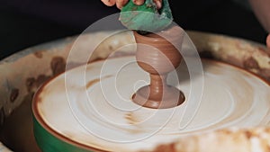 Hands Mould clay product Rotating On Potter`S Wheel And Moisten With Its Sponge craft factory authentic. Close up