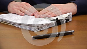 Hands move a stack of documents to the pen on the table