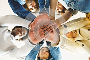 Hands of a multi-ethnic group of friends joined together as a sign of support and teamwork.