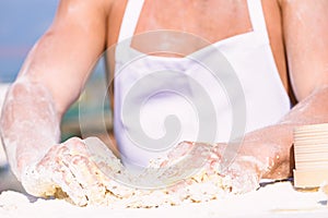 Hands of muscular baker or cook kneading raw sticky dough. Hands of chef cook working with sticky dough and flour