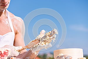 Hands of muscular baker or cook kneading raw sticky dough. Hands of chef cook working with sticky dough and flour