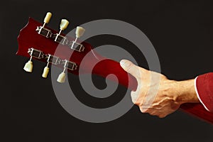 Hands of musician behind the guitar neck on dark background