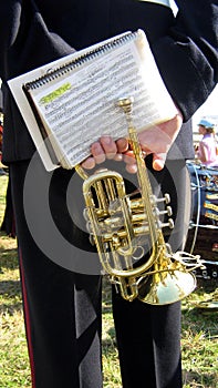 Hands of a musician carrying trumpet and a song book in an event, concert, or show