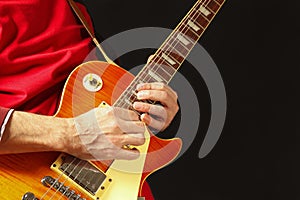 Hands of musician playing the electric guitar on dark background