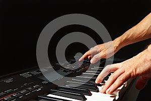 Hands of musician playing the electronic synthesizer on black background
