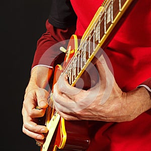 Hands of musician playing the guitar on dark background