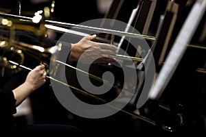 Hands of musicians played the trombone in the orchestra