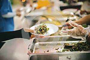 The hands of the needy holding a container to receive free charity food from volunteers : the concept of food assistance