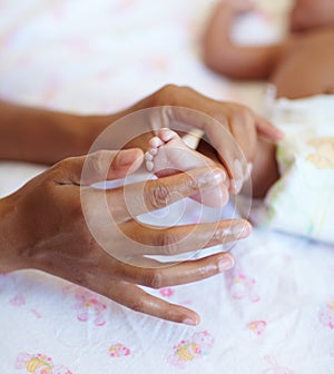 Hands, newborn and closeup of a baby foot with mother rubbing for comfort, care and love. Childcare, cute and zoom of a