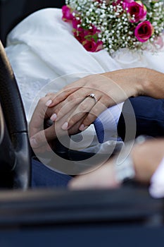 Hands of newlyweds in cabrio