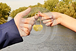 Hands of the newlyweds hold a romantic sign of their love padlock