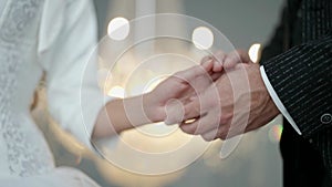 hands of newlyweds in wedding day, closeup view, man is holding palm of young bride