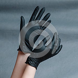 Hands in nitrile gloves of gold color on a gray background with a gradient