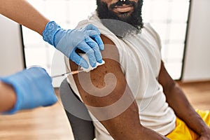 Hands of nurse woman injecting covid-19 vaccine to african amercian man at the clinic