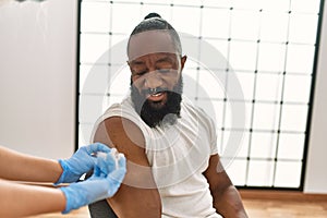 Hands of nurse woman injecting covid-19 vaccine to african amercian man at the clinic
