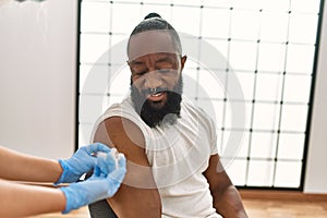 Hands of nurse woman injecting covid-19 vaccine to african amercian man at the clinic photo