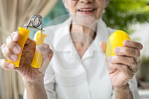 Hands of old elderly doing finger,palm and wrist exercise with rubber ball,spring hand gripper,stretch finger,squeeze with hand photo