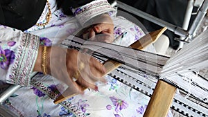 Hands of an old Emirati lady using traditional weaving machine