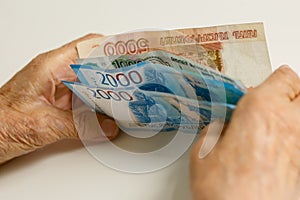 The hands of the old man are sorted by large denominations. Russia.