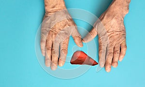 hands of an old man and a symbol of the liver organ on a blue background. concept of liver health, hepatitis prevention, liver