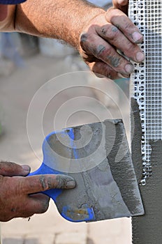 Hands of an old manual worker with wall plastering tools renovating house