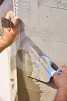 Hands of an old manual worker with wall plastering tools renovating house