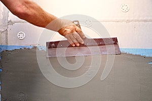Hands of an old manual worker with wall plastering tools renovating house