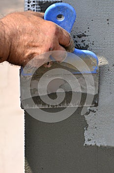 Hands of an old manual worker with wall plastering tools renovating house