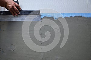 Hands of an old manual worker with wall plastering tools renovating house photo