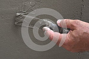 Hands of an old manual worker with wall plastering tools renovating house. Plasterer renovating outdoor walls and corners with