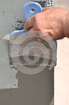 Hands of an old manual worker with wall plastering tools renovating house. Plasterer renovating outdoor walls and corners with