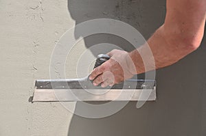 Hands of an old manual worker with wall plastering tools renovating house. Plasterer renovating outdoor walls and corners with