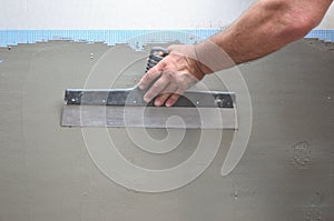 Hands of an old manual worker with wall plastering tools renovating house. Plasterer renovating outdoor walls and corners with