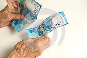 The hands of an old pensioner consider money of a large size. The hands of a man are old, decrepit.