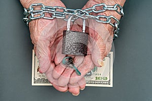 Hands of an old woman 90 years close up. The key and lock, 100 dollars in the hands of an old woman. The old woman`s hands are