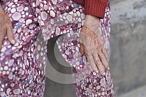 Hands of an old woman in bright clothes