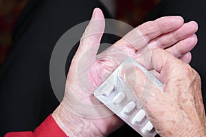 Hands of an old woman close-up. The old woman unpacks the tablets before use