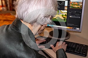 Hands of an old woman on a computer keyboard