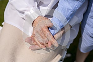 The hands of an old woman hold the hand of a grandson