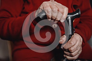 Hands old woman holding cane, skin wrinkled.