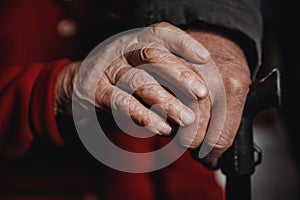 Hands of an old woman and man holding cane, skin wrinkled